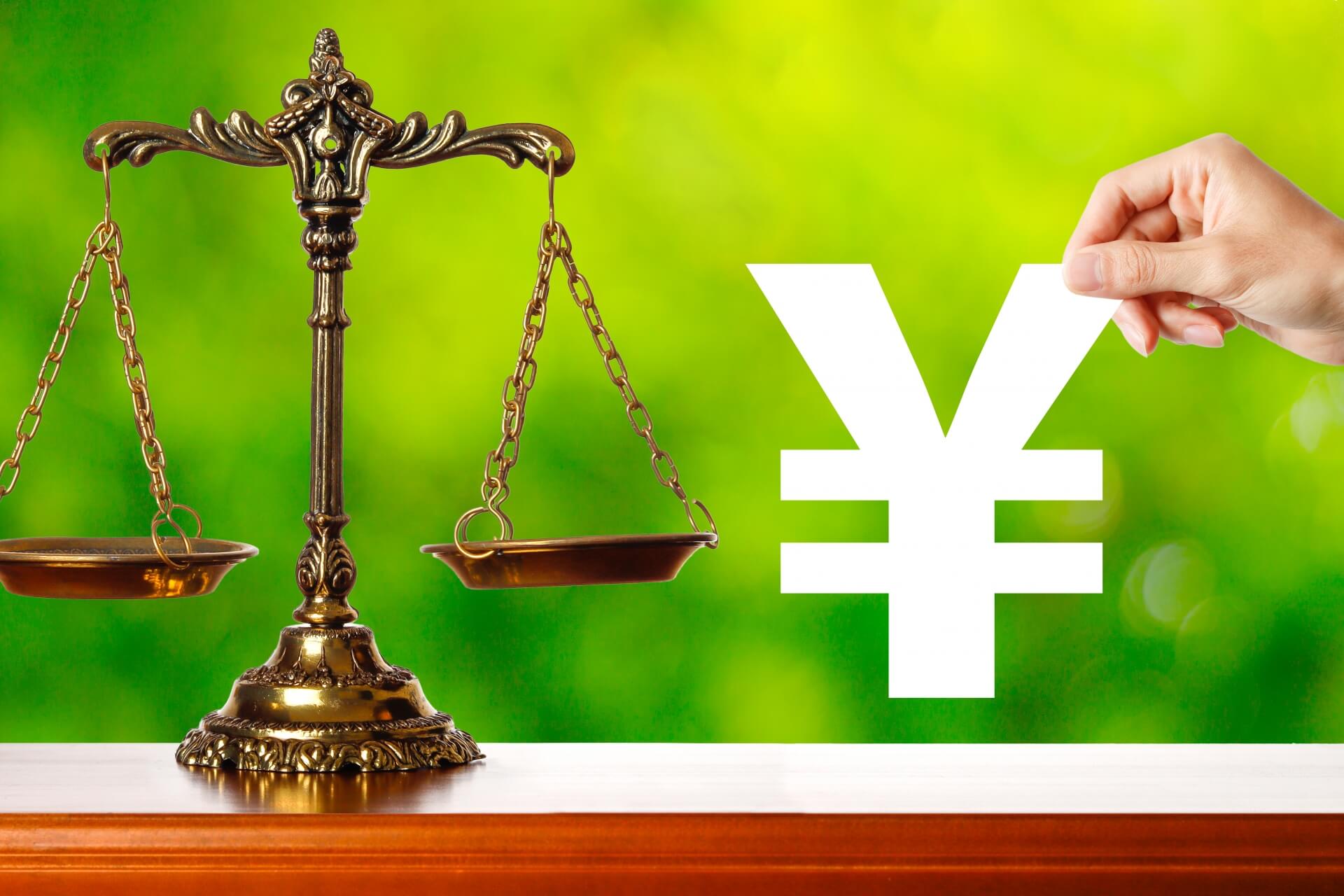 天秤と手に持たれた円記号